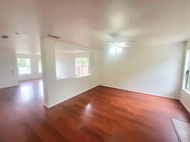 an empty room with wooden floor and windows