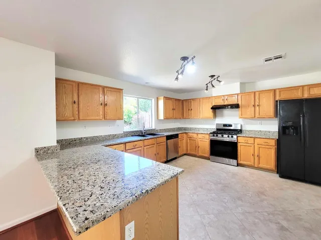a large kitchen with stainless steel appliances granite countertop a sink stove and refrigerator