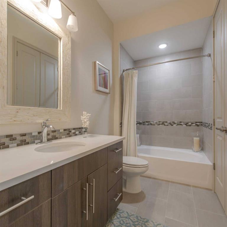 a bathroom with a bathtub shower sink vanity mirror and toilet
