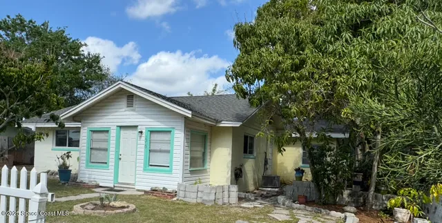 a view of a house with brick walls plants and large tree