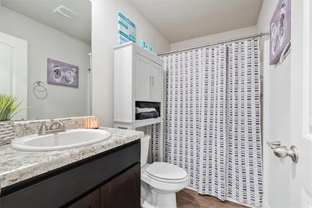 a bathroom with a granite countertop toilet sink and mirror