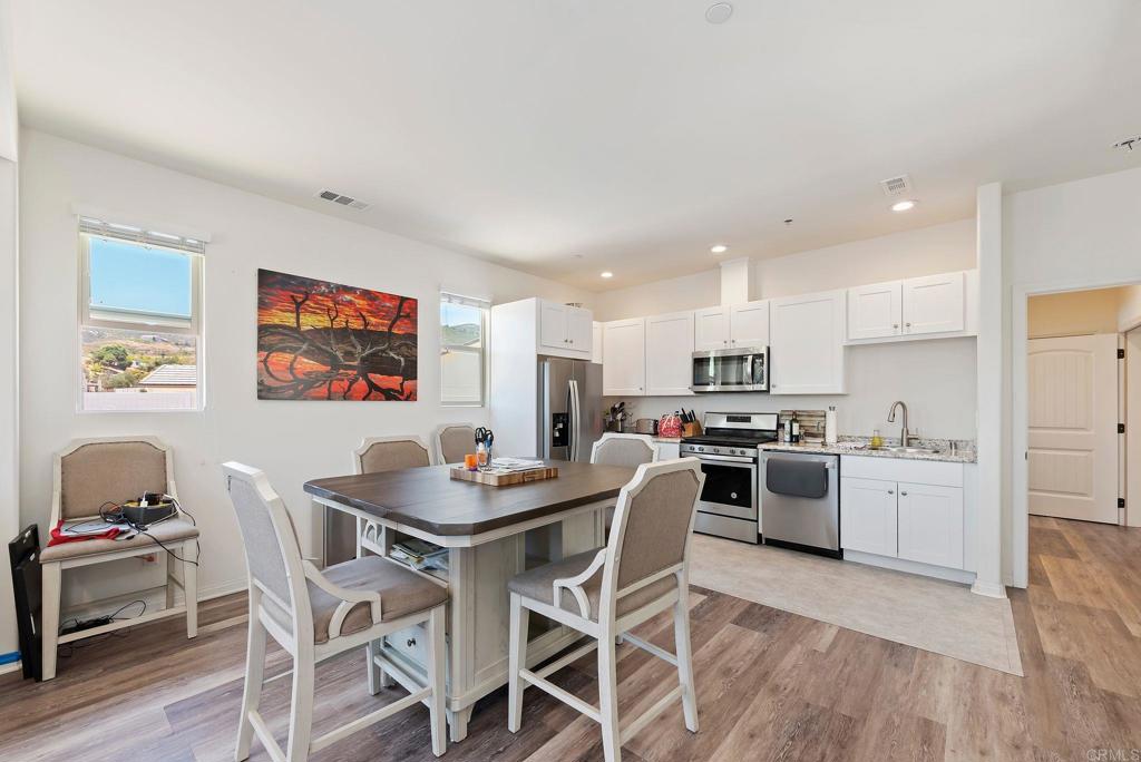 22089 Gallop Way Escondido, CA 92029 - Photo 24 of 43 a kitchen that has a dining table wooden floor stainless steel appliances and cabinets