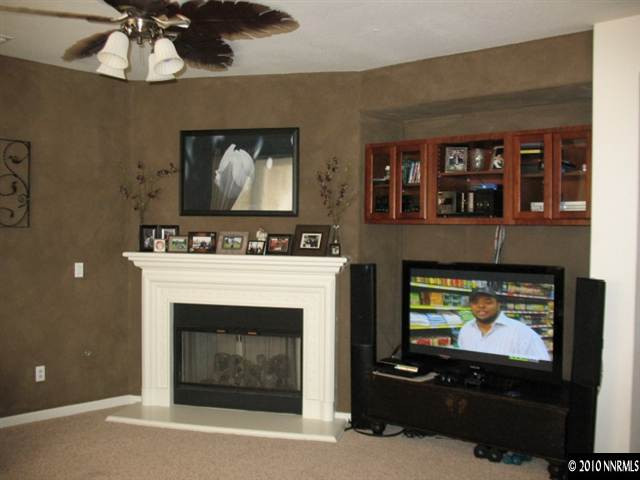 10612 Fire Poppy Circle Reno, NV 89521 - Photo 3 of 9 a living room with a fireplace a flat screen tv and a chandelier