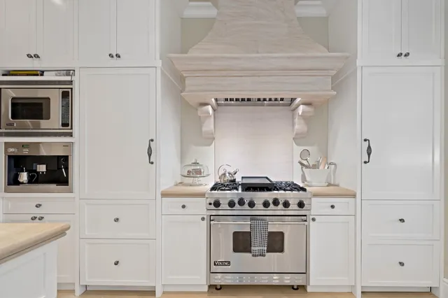 a kitchen with stainless steel appliances a stove and white cabinets