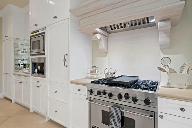 a white kitchen with stainless steel appliances granite countertop a stove and a sink