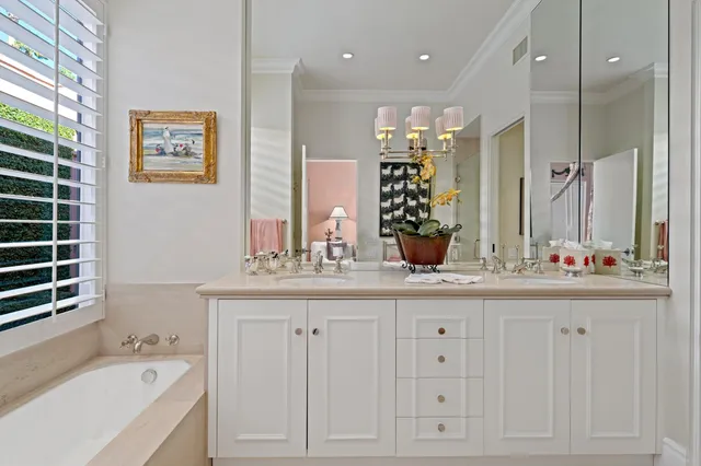 a bathroom with a double vanity sink a large mirror a bathtub and next to a window