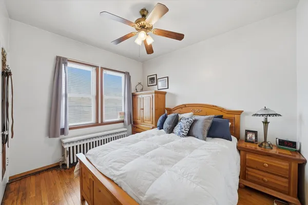 a bedroom with a bed and a dresser with wooden floor