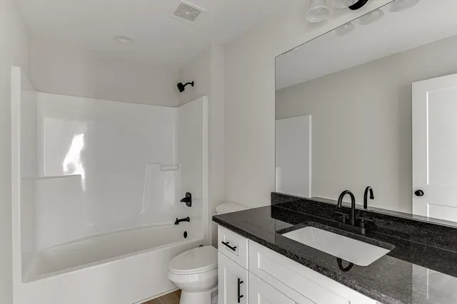a bathroom with a granite countertop sink a toilet and shower