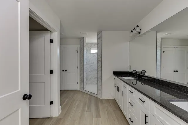 a bathroom with a granite countertop sink a mirror and shower