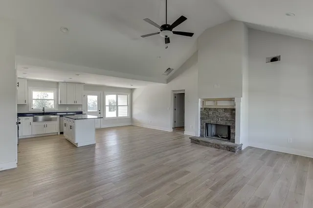 a view of empty room with wooden floor and a kitchen