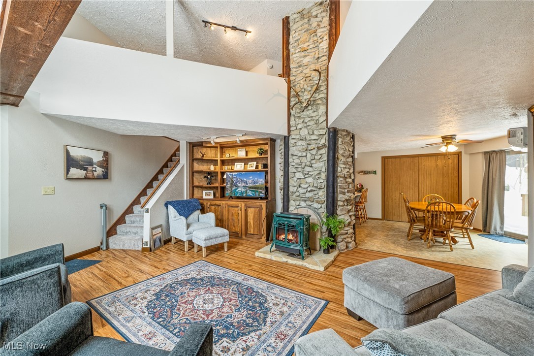 86523 North Bay Road Scio, OH 43988 - Photo 6 of 25 Living room with a wood stove, a textured ceiling, rail lighting, stairway, and a ceiling fan