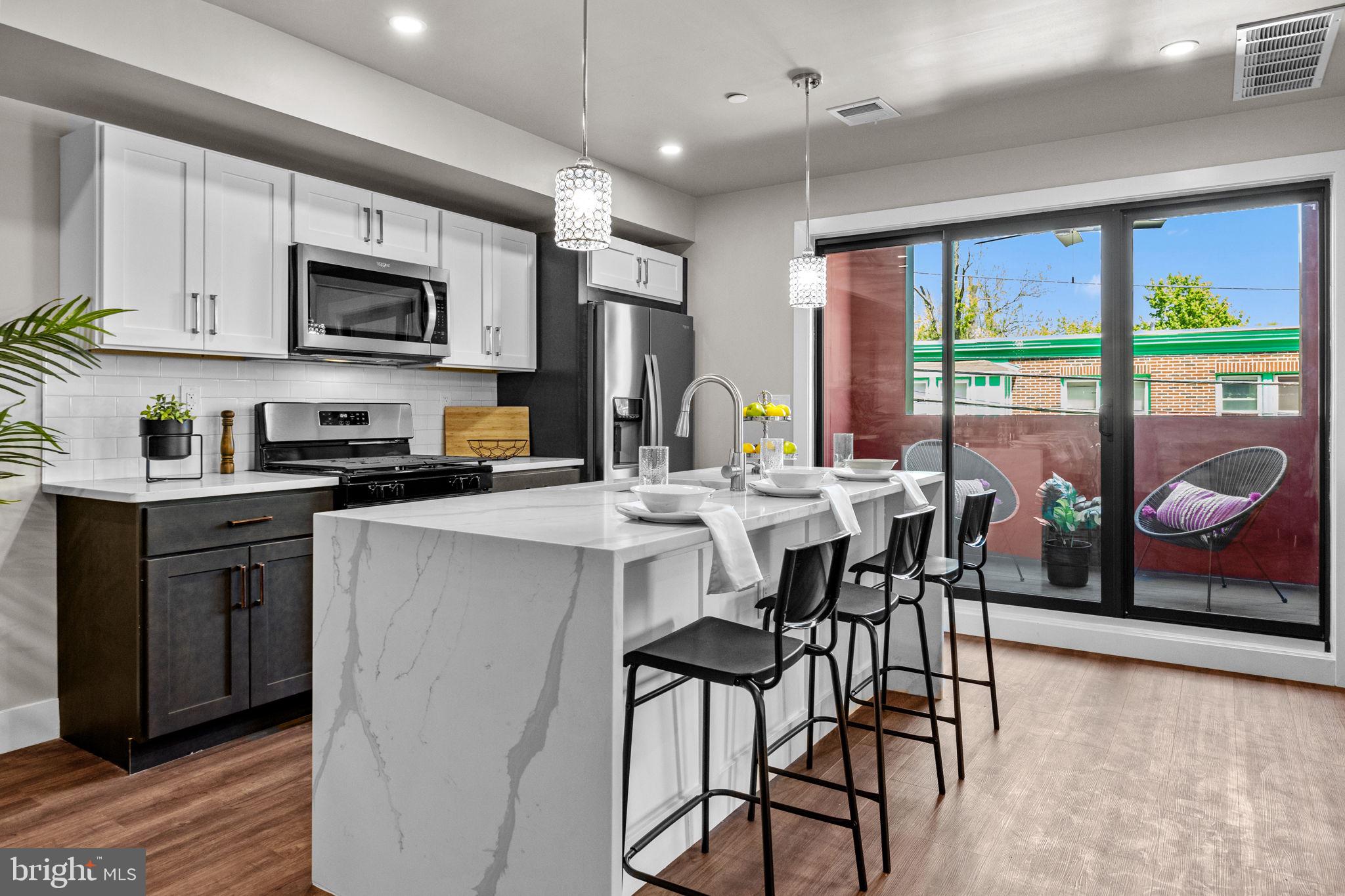 77 East Pastorius Street, Unit 1 Philadelphia, PA 19144 - Photo 8 of 43 a kitchen with stainless steel appliances granite countertop a stove top oven a sink a dining table and chairs with wooden floor