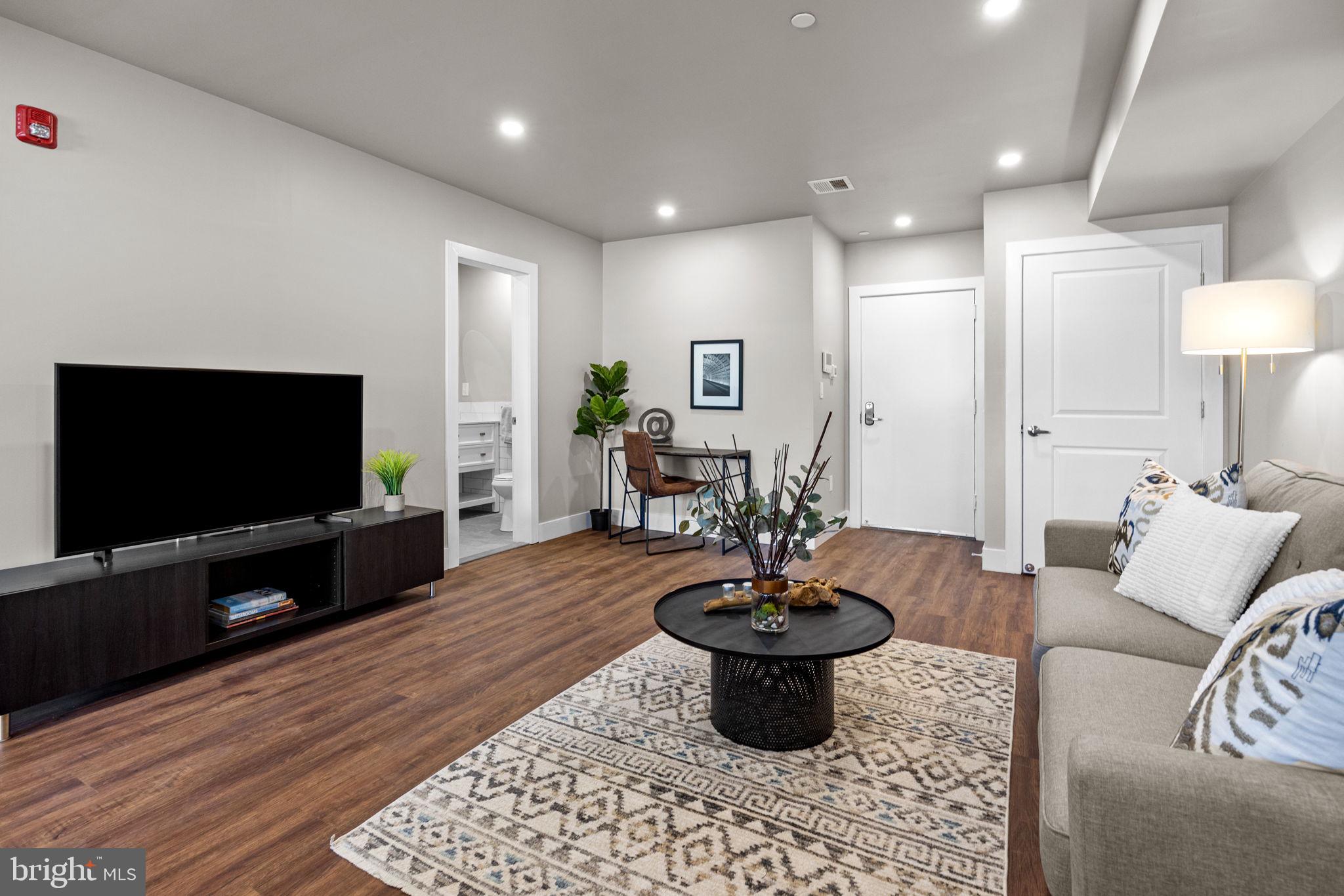 77 East Pastorius Street, Unit 1 Philadelphia, PA 19144 - Photo 9 of 43 a living room with furniture a flat screen tv and kitchen view