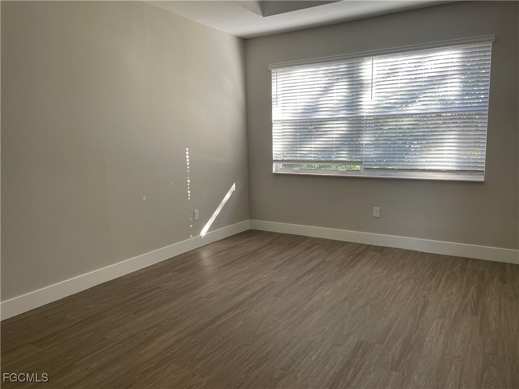 7024 Ambrosia Lane, Unit 902 Naples, FL 34119 - Photo 9 of 10 an empty room with wooden floor and windows