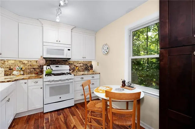a kitchen with stainless steel appliances a white table and chairs in it