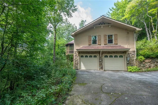 a front view of house with yard and trees all around