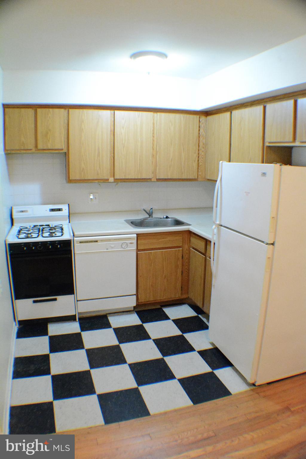 3411 Cresson Street, Unit 4 Philadelphia, PA 19129 - Photo 3 of 16 a kitchen with a checkered floor and white cabinets