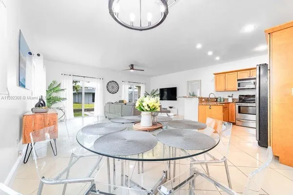 a dining room with furniture a chandelier and kitchen view