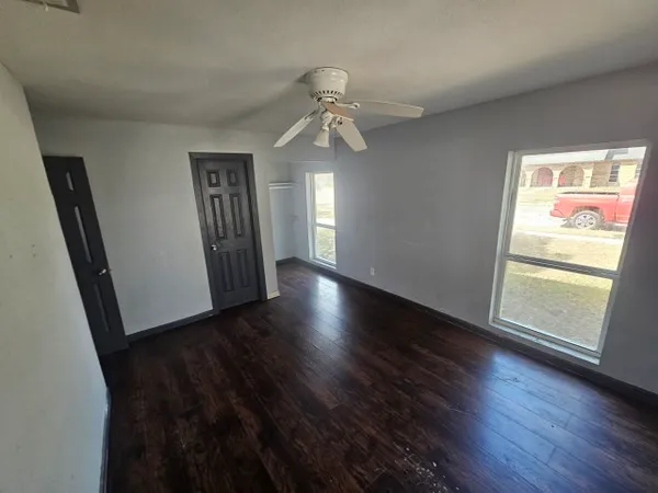 a view of an empty room with wooden floor and a window