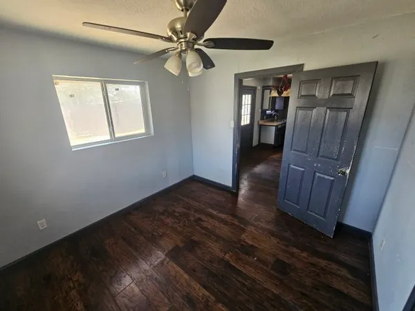 a view of a livingroom with wooden floor a ceiling fan and a window