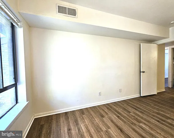 a view of an empty room with wooden floor and a window