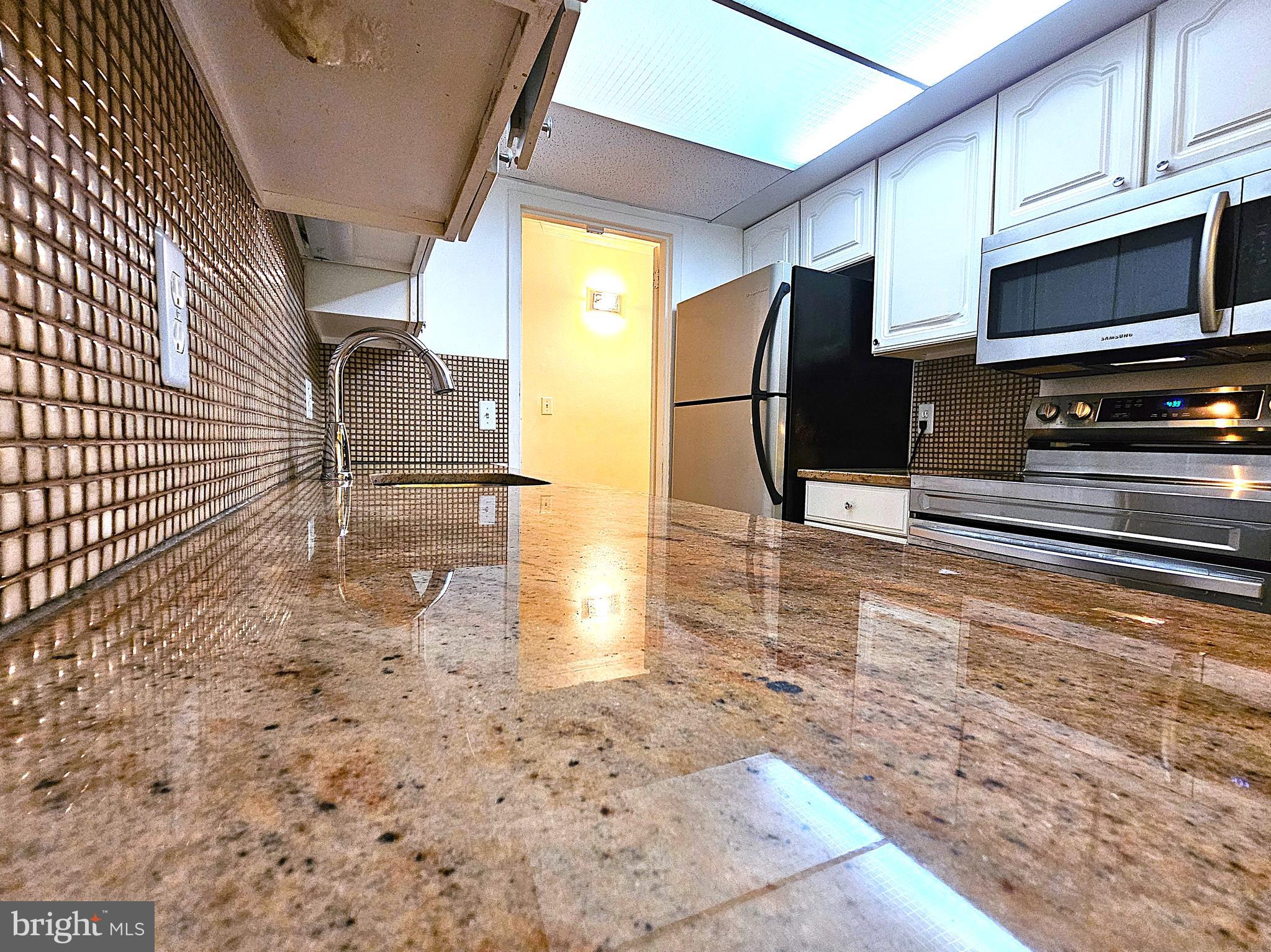 2239 Castle Rock Square, Unit 21C Reston, VA 20191 - Photo 2 of 30 a kitchen with granite countertop a stove a microwave and a sink