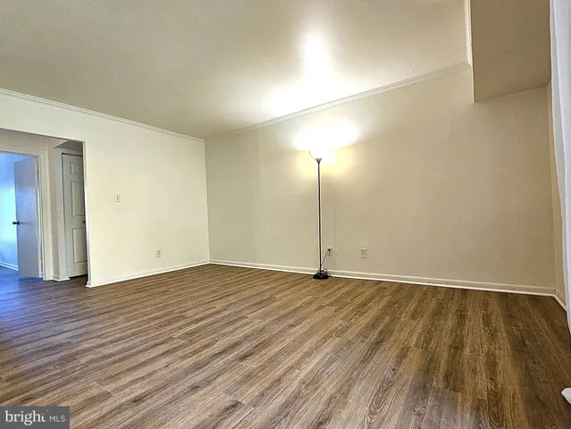 an empty room with wooden floor and fan