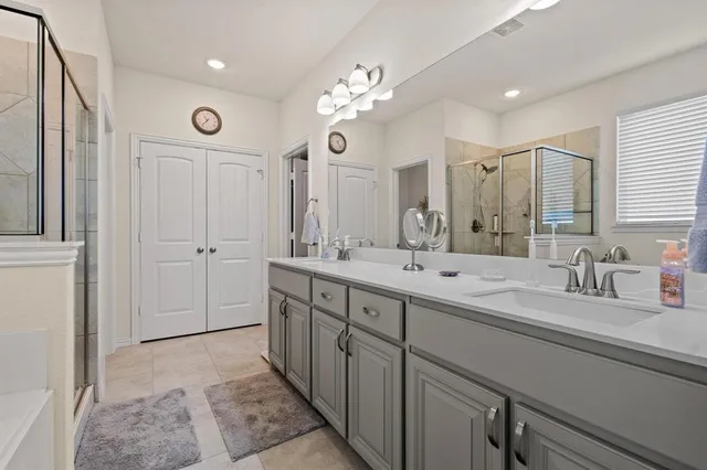 a spacious bathroom with a double vanity sink a mirror and a shower