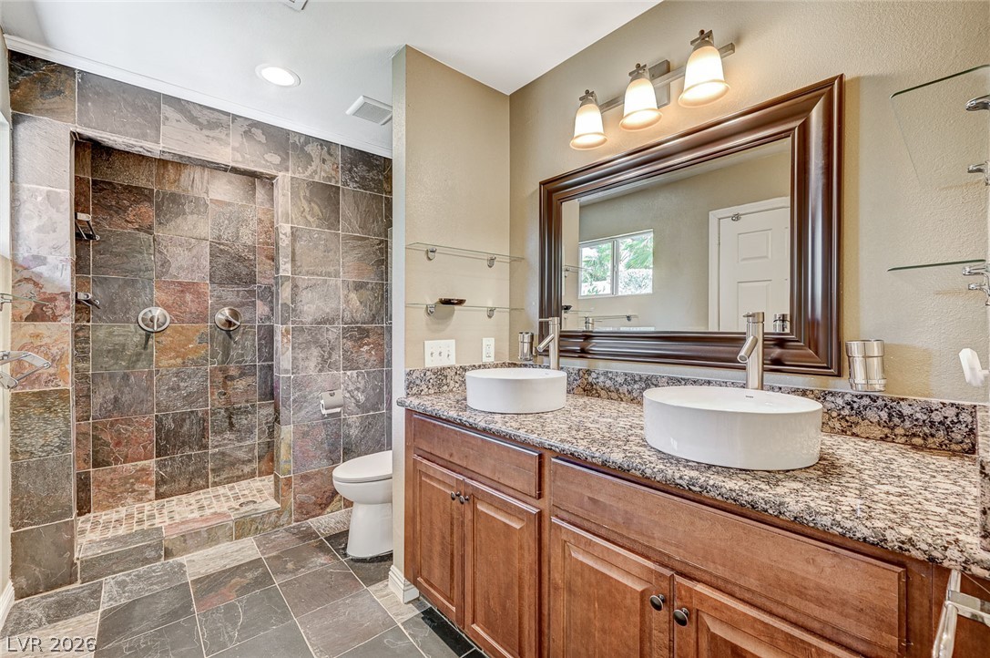 4153 Woodcrest Road Las Vegas, NV 89121 - Photo 31 of 58 Granite counters and dual vessel sinks complement the slate-tiled walk-in shower in this well-appointed bath.