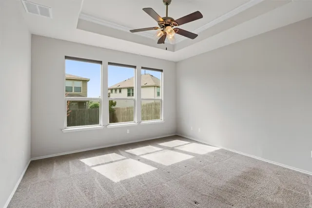 an empty room with chandelier fan and windows