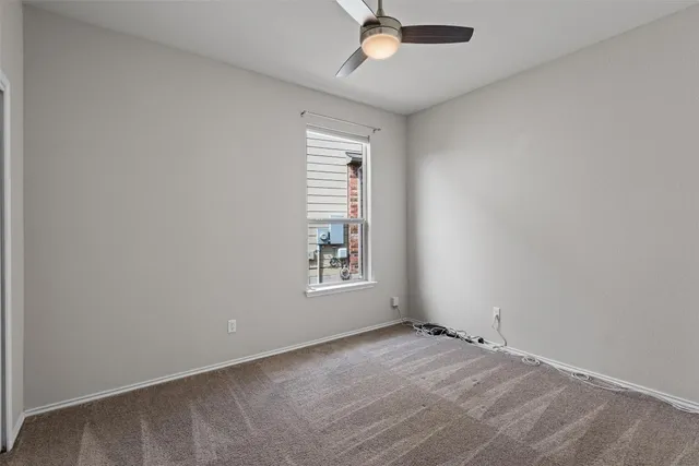 an empty room with a window and ceiling fan