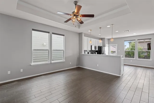 a view of a kitchen with furniture a ceiling fan and wooden floor