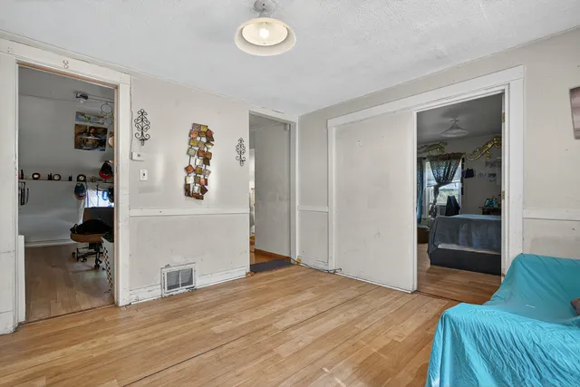 a view of a livingroom with wooden floor and a bedroom