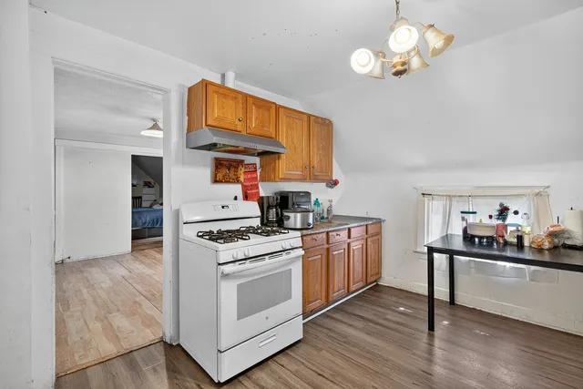 a kitchen with stainless steel appliances granite countertop a stove a sink dishwasher and a refrigerator with wooden floor