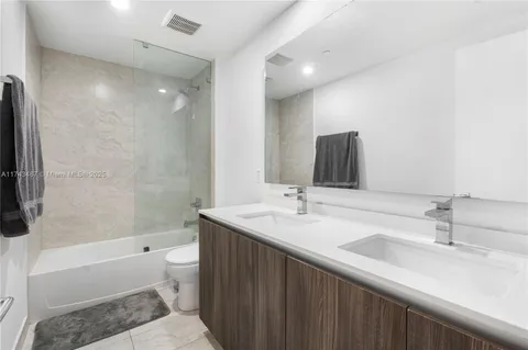 a bathroom with a double vanity sink toilet mirror and bathtub