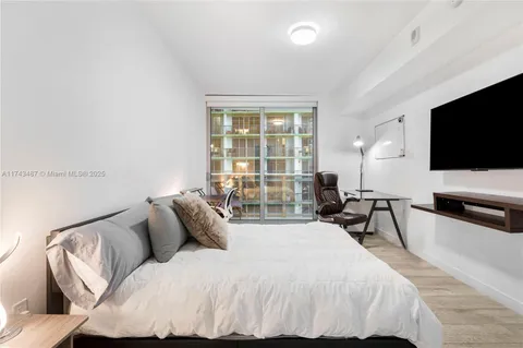 a spacious bedroom with a bed and a flat screen tv