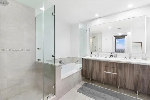 a bathroom with a double vanity sink mirror and bathtub