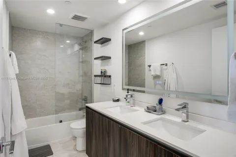 a bathroom with double vanity sink toilet a shower and a mirror