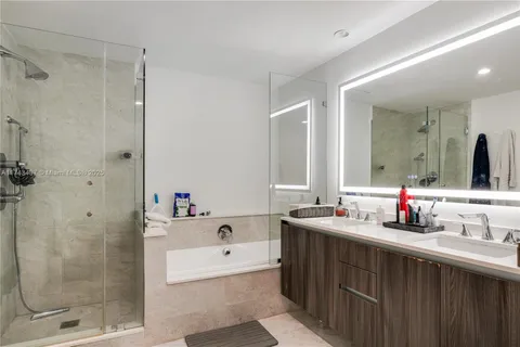 a bathroom with a tub sink mirror and shower