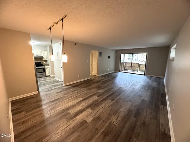 a view of an empty room with window and wooden floor