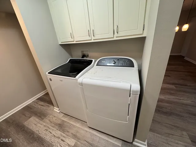 a utility room with wooden floor washer and dryer
