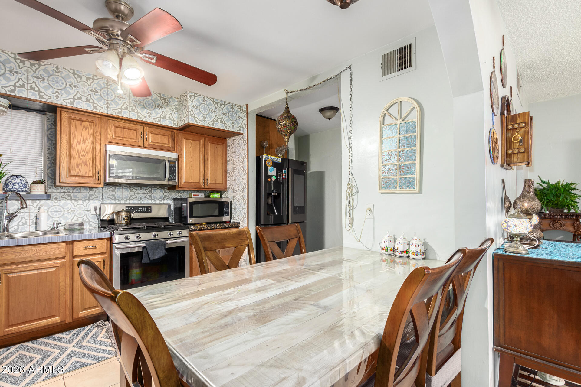 2825 North 33rd Place Phoenix, AZ 85008 - Photo 11 of 27 a kitchen with stainless steel appliances granite countertop a stove top oven a sink a dining table and chairs with wooden floor