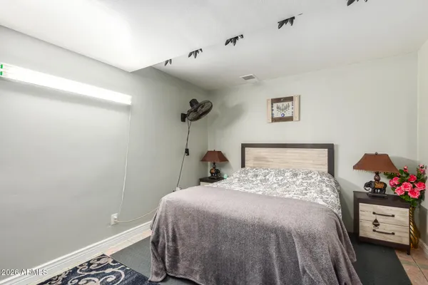 a bedroom with a bed and a potted plant on the dresser