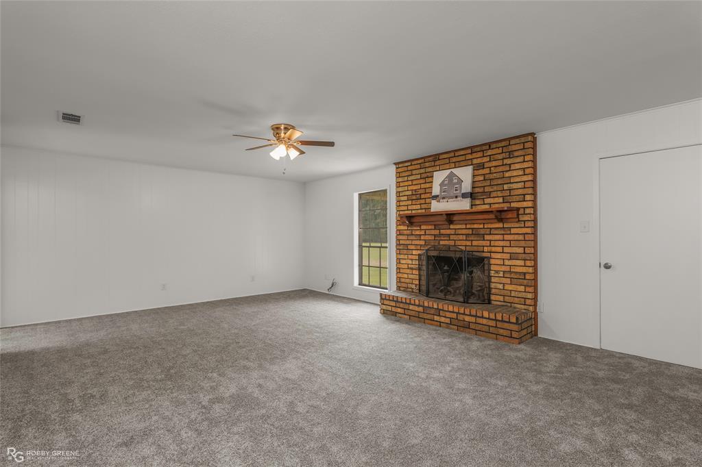 1303 Young Road Benton, LA 71006 - Photo 9 of 34 Unfurnished living room with a brick fireplace, a ceiling fan, and carpet