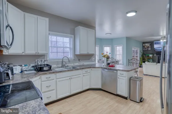 a kitchen with stainless steel appliances granite countertop a refrigerator sink and white cabinets