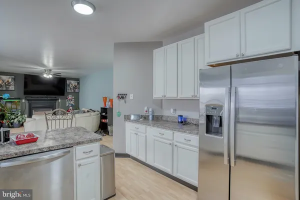 a kitchen with stainless steel appliances granite countertop a stove top oven a refrigerator a dining table and chairs with wooden floor