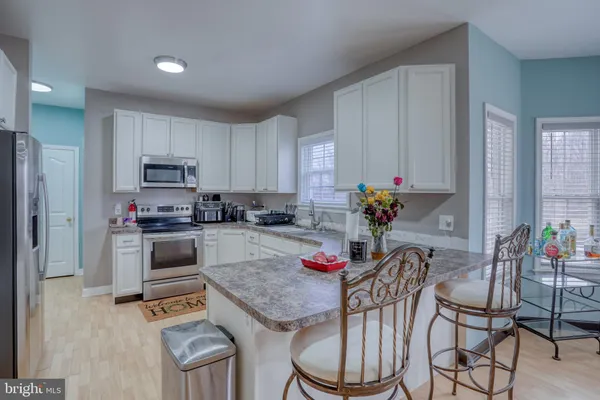 a kitchen with stainless steel appliances kitchen island granite countertop a table chairs in it and white cabinets