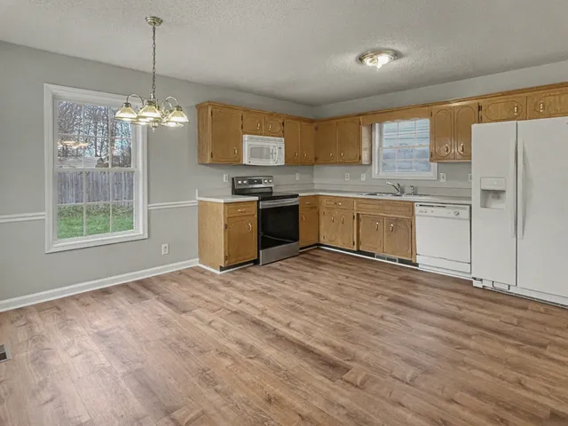 a large kitchen with granite countertop a stove top oven a sink dishwasher and a refrigerator