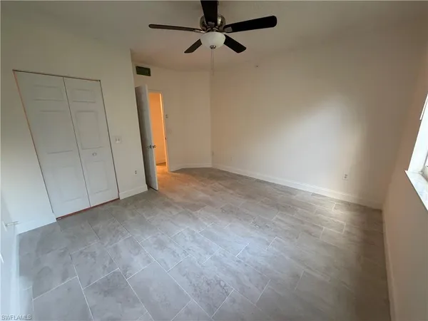 an empty room with a ceiling fan and carpet