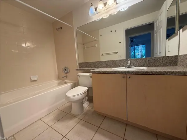 a bathroom with a granite countertop sink a toilet mirror and bathtub